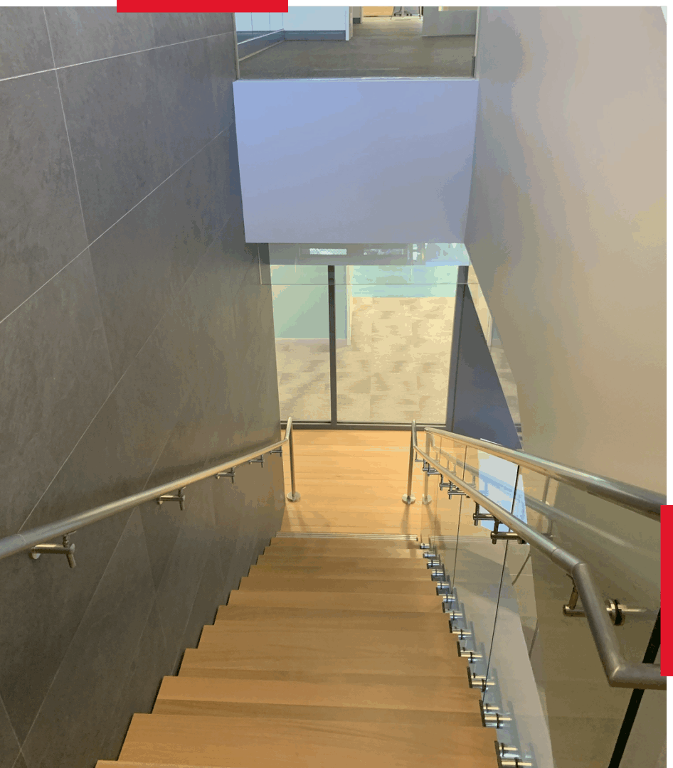 Wooden staircase with metal railings leading to a balcony and glass doors.