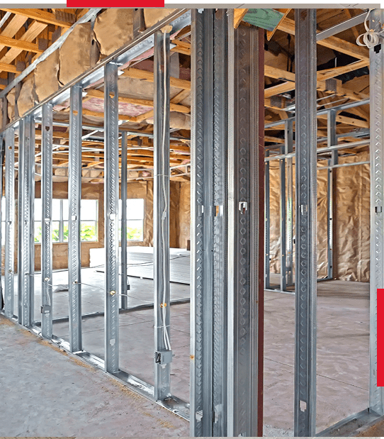 Interior framing of a building under construction with metal studs and wooden ceiling beams.