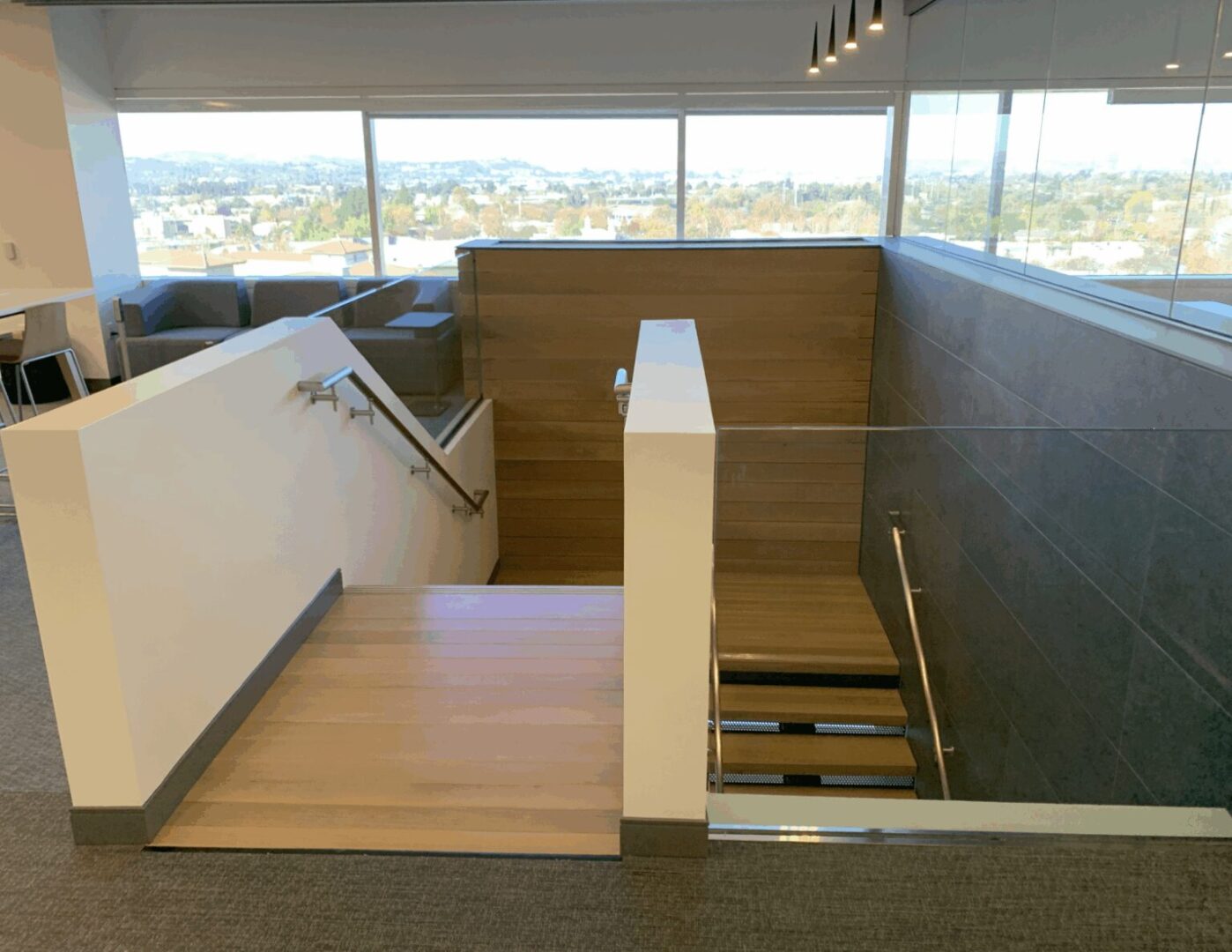 Staircase with wooden steps and glass railing in a modern building.