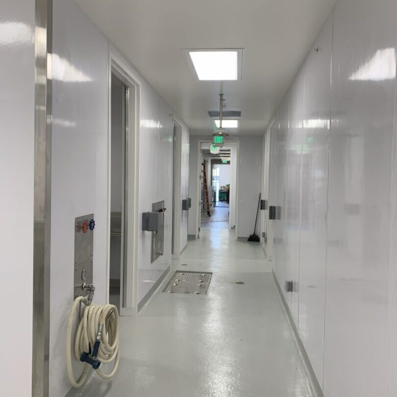Clean white hallway with doors and ceiling lights.