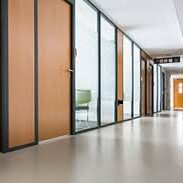 Modern office corridor with glass and wooden doors.